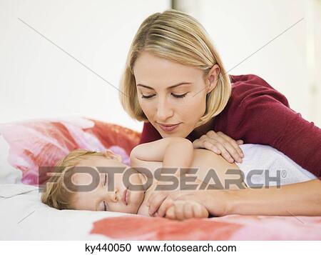 Stock Image - Woman looking at her baby sleeping on the bed. Fotosearch