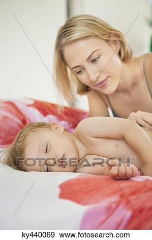 Woman looking at her baby sleeping on the bed View Large Photo Image Stock Photo - Woman looking at her baby sleeping on the bed. Fotosearch