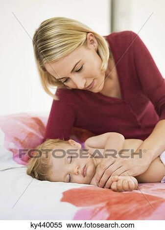 Woman looking at her baby sleeping on the bed View Large Photo Image Stock Photography - Woman looking at her baby sleeping on the bed. Fotosearch