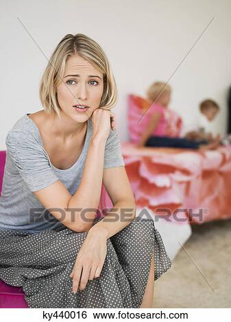 Woman looking worried with her children in the background View Large Photo Image Stock Photograph - Woman looking worried with her children in the background. Fotosearch