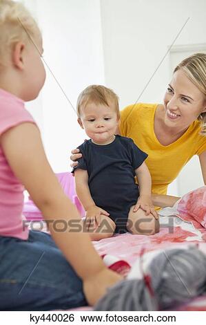 Woman playing with her children on the bed View Large Photo Image Stock Photograph - Woman playing with her children on the bed. Fotosearch