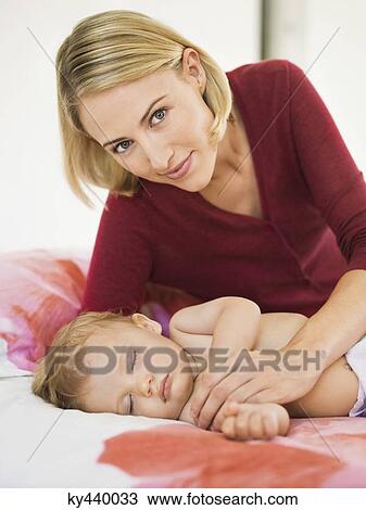 Woman reclining beside her baby sleeping on the bed View Large Photo Image Stock Image - Woman reclining beside her baby sleeping on the bed. Fotosearch