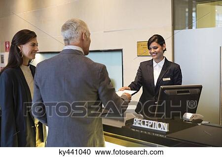 Business couple checking into hotel View Large Photo Image Stock Image - Business couple checking into hotel. Fotosearch