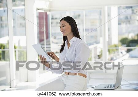 Businesswoman holding a digital tablet and smiling in an office View Large Photo Image Stock Image - Businesswoman holding a digital tablet and smiling in an office. Fotosearch