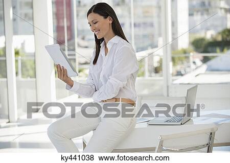 Businesswoman holding a digital tablet and smiling in an office View Large Photo Image Stock Photo - Businesswoman holding a digital tablet and smiling in an office. Fotosearch