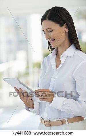 Businesswoman using a digital tablet in an office View Large Photo Image Stock Photo - Businesswoman using a digital tablet in an office. Fotosearch