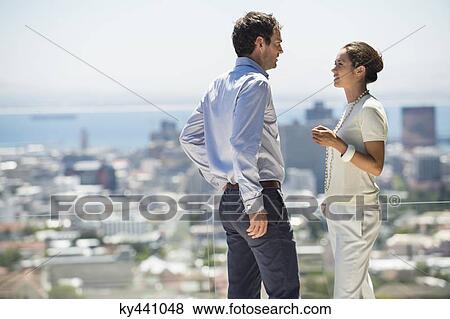 Couple discussing on a terrace with city in the background View Large Photo Image Stock Photo - Couple discussing on a terrace with city in the background. Fotosearch