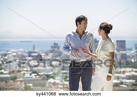 Couple discussing on a terrace with city in the background View Large Photo Image Stock Photo - Couple discussing on a terrace with city in the background. Fotosearch