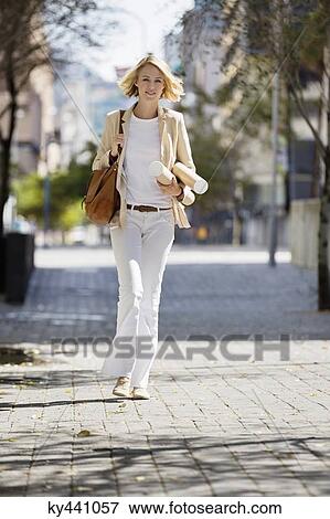 Female architect walking on a street with paper rolls View Large Photo Image Stock Photo - Female architect walking on a street with paper rolls. Fotosearch