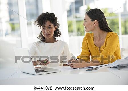 Female friends working on a laptop at home View Large Photo Image Stock Image - Female friends working on a laptop at home. Fotosearch