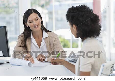 Stock Photo - Female patient signing a document in doctor's office. Fotosearch