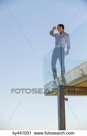 Man standing on the terrace and shielding his eyes View Large Photo Image Stock Image - Man standing on the terrace and shielding his eyes. Fotosearch