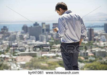 Man standing on the terrace using a mobile phone View Large Photo Image Stock Image - Man standing on the terrace using a mobile phone. Fotosearch