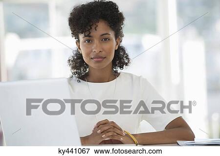 Portrait of a woman sitting in front of a laptop View Large Photo Image Stock Photo - Portrait of a woman sitting in front of a laptop. Fotosearch