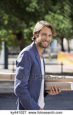 Portrait of an architect carrying paper rolls and smiling View Large Photo Image Stock Photo - Portrait of an architect carrying paper rolls and smiling. Fotosearch