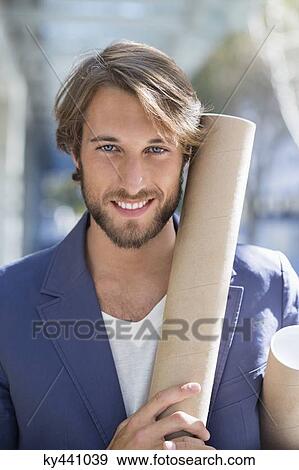 Portrait of an architect holding paper rolls and smiling View Large Photo Image Stock Photo - Portrait of an architect holding paper rolls and smiling. Fotosearch