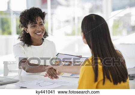 Stock Image - Real estate agent shaking hands with a woman. Fotosearch