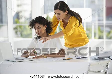 Picture - Two female friends reviewing bill on a laptop at home. Fotosearch