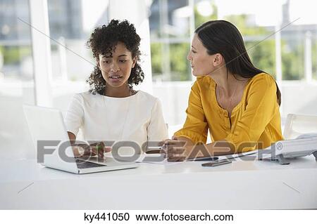 Two female friends working on a laptop at home View Large Photo Image Stock Image - Two female friends working on a laptop at home. Fotosearch