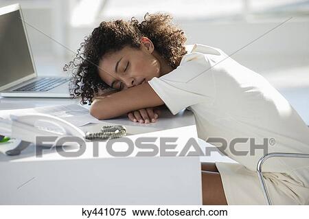 Stock Photography - Woman napping with her head resting on desk. Fotosearch