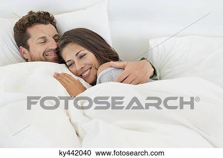 Smiling couple lying on the bed View Large Photo Image Stock Image - Smiling couple lying on the bed. Fotosearch