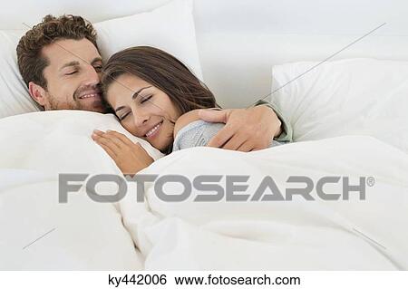 Smiling couple lying on the bed View Large Photo Image Stock Photograph - Smiling couple lying on the bed. Fotosearch