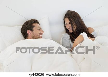 Smiling couple lying on the bed View Large Photo Image Stock Photograph - Smiling couple lying on the bed. Fotosearch