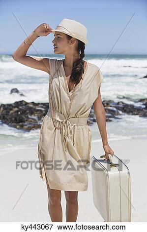 Beautiful woman carrying a suitcase on the beach View Large Photo Image Stock Photo - Beautiful woman carrying a suitcase on the beach. Fotosearch