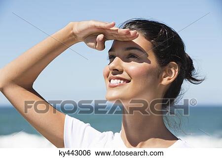 Beautiful woman shielding eyes on the beach View Large Photo Image Stock Photograph - Beautiful woman shielding eyes on the beach. Fotosearch