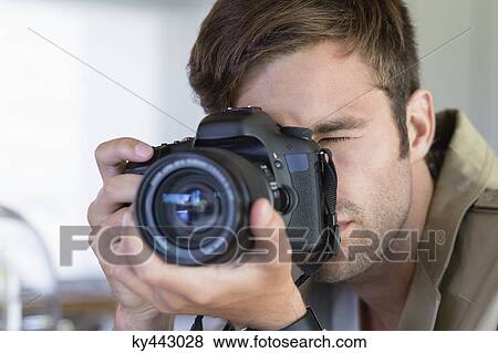 Close-up of a man photographing with a camera View Large Photo Image Stock Photo - Close-up of a man photographing with a camera. Fotosearch