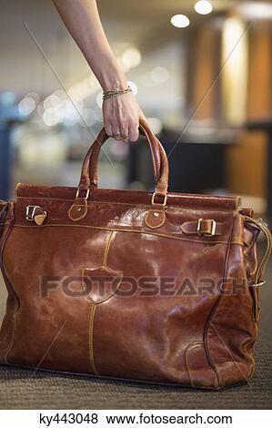 Close-up of a woman's hand picking up a leather purse View Large Photo Image Stock Photo - Close-up of a woman's hand picking up a leather purse. Fotosearch