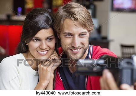 Stock Image - Couple filming themselves with a home video camera. Fotosearch