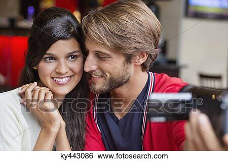 Stock Photograph - Couple filming themselves with a home video camera. Fotosearch