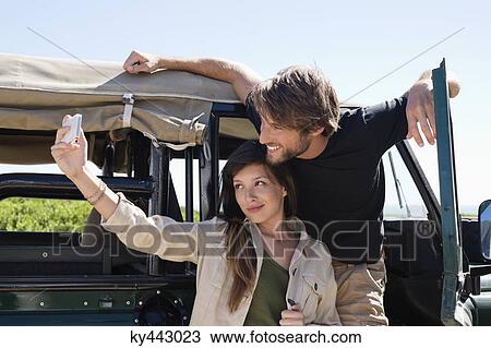 Couple taking a picture of themselves with a smartphone on SUV View Large Photo Image Stock Image - Couple taking a picture of themselves with a smartphone on SUV. Fotosearch