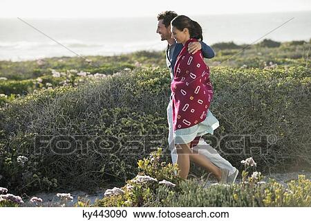 Stock Image - Couple walking on the beach. Fotosearch