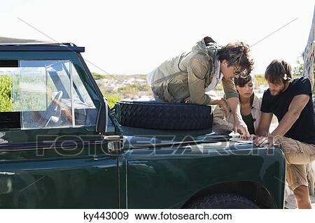 Friends looking at map beside a SUV View Large Photo Image Stock Photo - Friends looking at map beside a SUV. Fotosearch