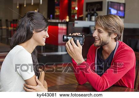 Stock Image - Man filming his girlfriend with a home video camera. Fotosearch