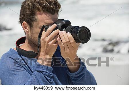 Stock Photo - Man photographing on the beach. Fotosearch