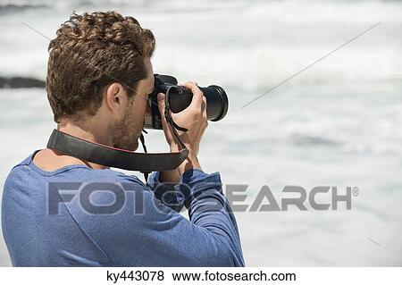 Man photographing on the beach View Large Photo Image Stock Photo - Man photographing on the beach. Fotosearch