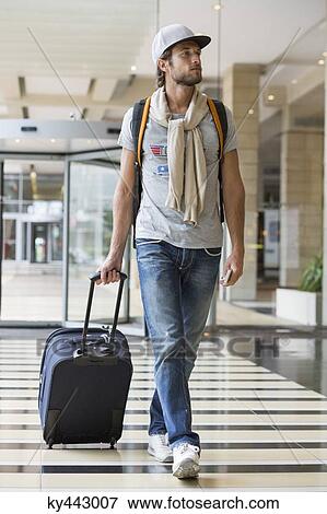Man pulling his luggage at an airport View Large Photo Image Stock Photo - Man pulling his luggage at an airport. Fotosearch