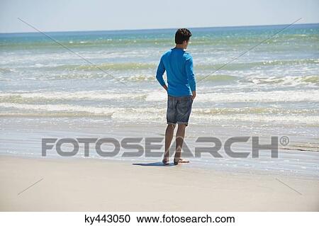 Man standing on the beach and looking at the sea View Large Photo Image Stock Image - Man standing on the beach and looking at the sea. Fotosearch