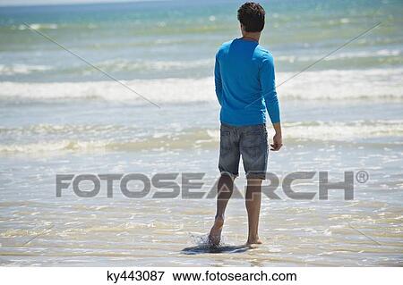 Man standing on the beach and looking at the sea View Large Photo Image Stock Photo - Man standing on the beach and looking at the sea. Fotosearch