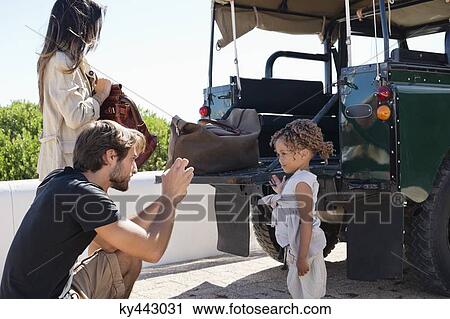 Man taking a picture of his daughter with a smartphone beside a SUV View Large Photo Image Stock Image - Man taking a picture of his daughter with a smartphone beside a SUV. Fotosearch