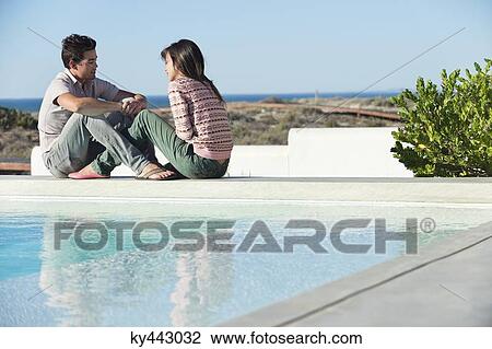 Romantic couple sitting at the poolside on the beach View Large Photo Image Stock Image - Romantic couple sitting at the poolside on the beach. Fotosearch