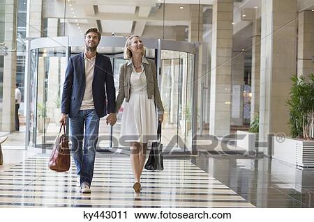 Smiling couple walking at an airport View Large Photo Image Stock Image - Smiling couple walking at an airport. Fotosearch