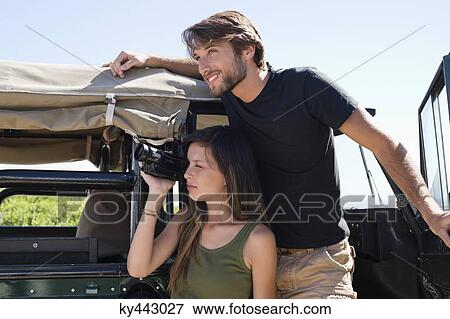 Woman filming with a video camera with her boyfriend on SUV View Large Photo Image Stock Photo - Woman filming with a video camera with her boyfriend on SUV. Fotosearch