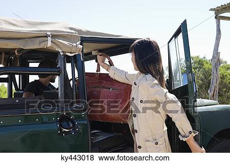 Woman putting handbag in SUV View Large Photo Image Stock Photo - Woman putting handbag in SUV. Fotosearch