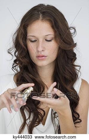 Stock Image - Close-up of a woman holding a hair conditioner. Fotosearch