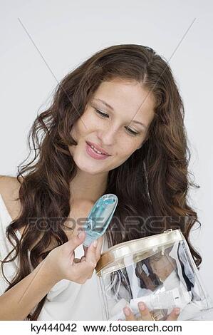 Stock Image - Close-up of a woman holding a make-up bag and smiling. Fotosearch
