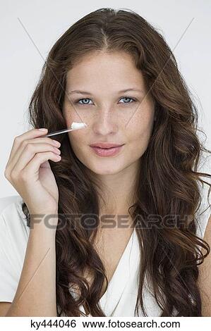 Stock Photograph - Portrait of a woman applying moisturizer cream on her face. Fotosearch